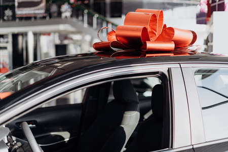 The new car is wrapped in a red bow. Beautiful gift conceptの写真素材