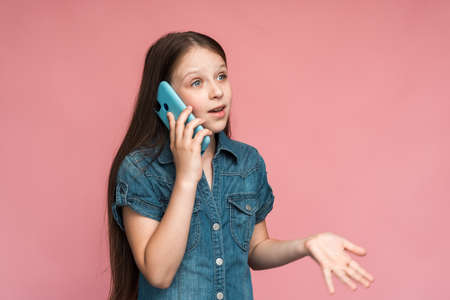 Cute little girl with long hair smiling joyfully while calling parents on cell phone. Good cellular, roaming, comfortable to use children mobile device conceptの写真素材