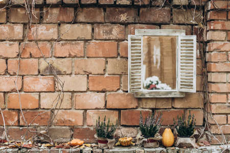 Autumn porch decor. Garland of autumn leaves, pumpkins and pots with plants on a brick facade background. Harvest conceptの写真素材