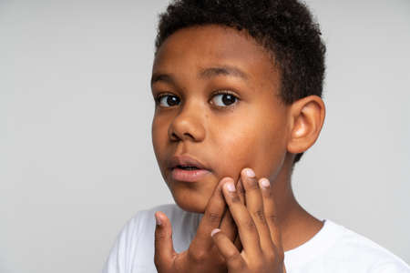 Dental problems. Portrait of unhealthy boy pressing sore cheek, suffering acute toothache, periodontal disease, cavities or jaw pain. Indoor studio shot isolated on white backgroundの写真素材
