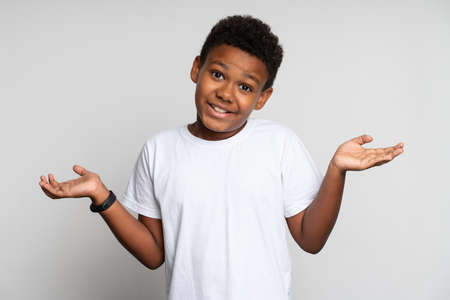 Misunderstanding. Portrait of little boy raising hands and asking question, while gesturing in bewilderment. Indoor studio shot, isolatedの写真素材