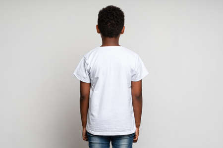 Back view of the multiracial boy wearing white T shirt. Childhood concept. Isolated on white background, studio shotの写真素材
