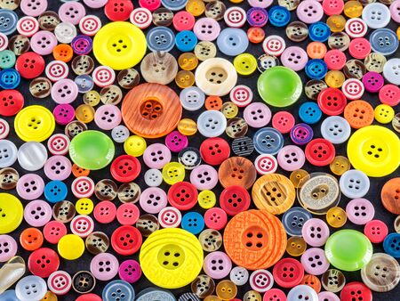 Colorful mixed sewing buttons on black background, flat lay. Top viewの写真素材