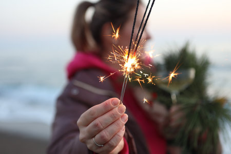 Young woman holding a sparkler on the background of the sea.の写真素材