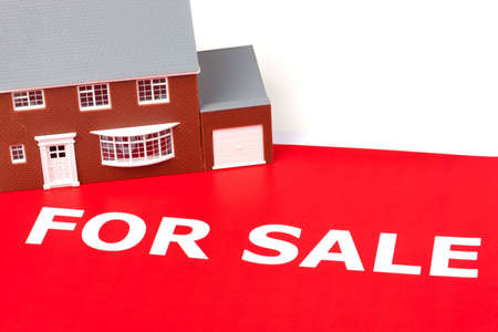 House sitting on a large red for sale signの写真素材
