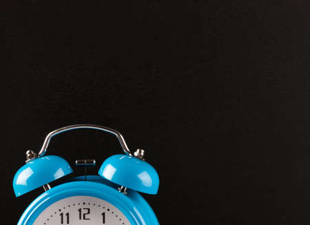 Top part of blue alarm clock with a chalk board behind it.の写真素材