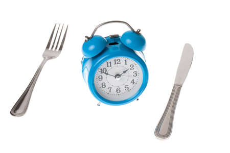 A knife and fork and alarm clock displaying the concept of meal timeの写真素材