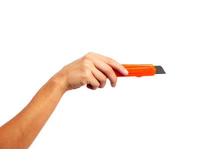 A female hand holding an orange craft knife on an isolated white backgroundの写真素材
