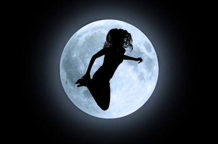 Black silhouette of jumping girl in front of moonの写真素材