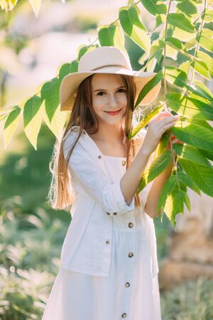 Nice little girl in white dress and hat smilingの写真素材
