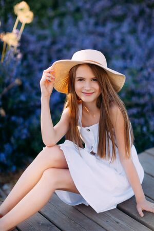 Portrait of little girl in white dress sitting in the parkの写真素材
