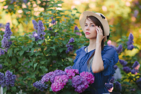 Portrait of young pretty girl with romantic look walking in lilac gardenの写真素材