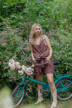 Nice girl rides retro bicycle in summer blooming parkの写真素材