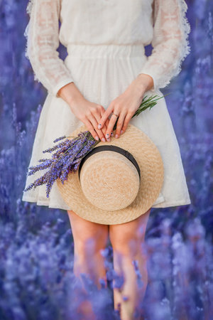 Calm scene with hads of young woman holding straw hat and lavender bouquet in handsの写真素材