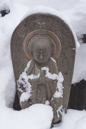 Japanese Jizo Buddha Statue in snow background, to protect the children by the faith of Japan.の写真素材