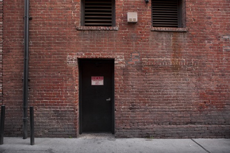 Back door entrance to an old brick building from the alley の写真素材