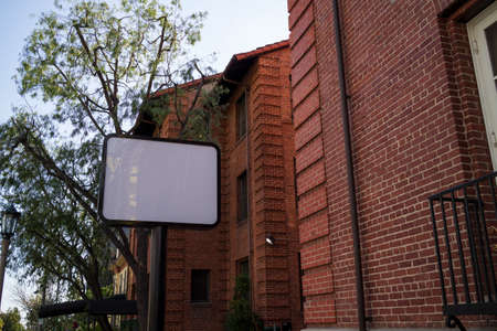 A street view looking at a black sign in front of brick buildings in a neighborhood in the afternoon.の写真素材