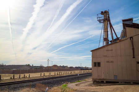 An abandoned factory across railroad tracks to a residential neighborhood in the afternoon.の写真素材