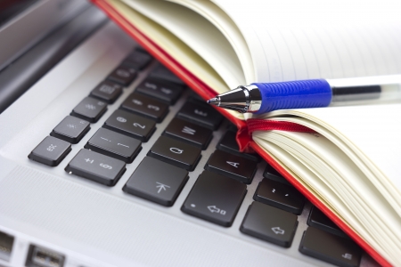 Red calendar or organizer or notebook and pen on the laptopの写真素材