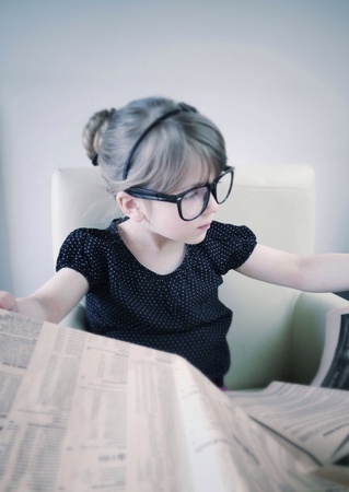 Little girl reading newspaperの素材