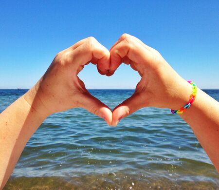 Hands heart shape against the seaの素材