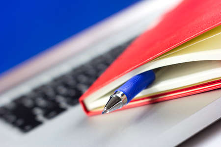 Red calendar or organizer or notebook and pen on the laptop