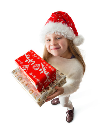 eight year girl in the santa claus hat holding christmas gifts, isolated on white backgroundの写真素材