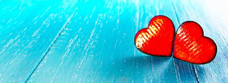 two ceramic hearts on the blue, wooden table