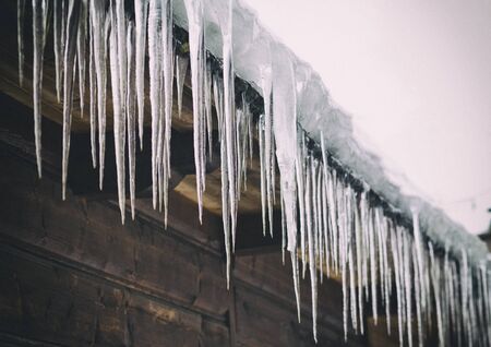 Icicles hanging from the roof of the old, rustic house.の写真素材