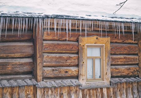 Icicles hanging from the roof of the old, rustic house.の写真素材