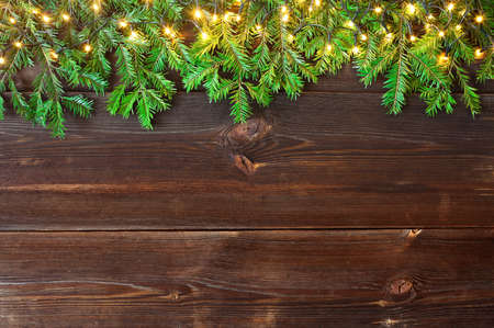 Fir branches and Christmas lights on wooden rustic planks. Christmas background. High angle view.の写真素材