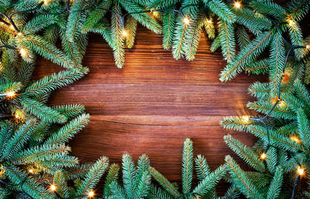 Christmas decoration. Fir tree frame witch christmas lights on rustic, wooden background. High angle view.の写真素材