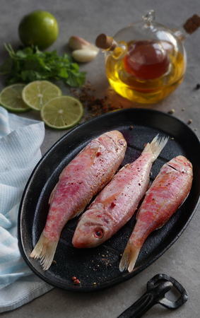 Fresh fish red mullet with lime and seasonings, with olive oil, garlic, spices, limeの写真素材