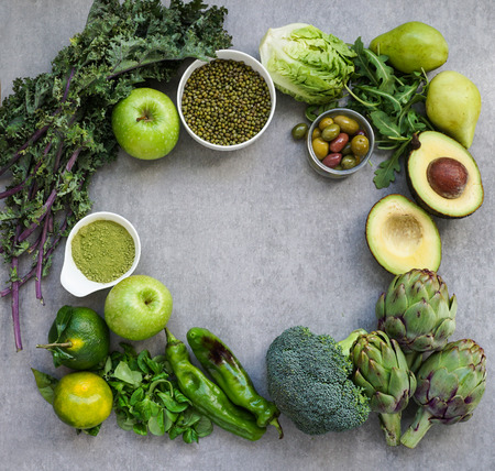 Healthy Green food selection for vegetarians: avocado, apples, broccoli, artichokes, tangerines, mung beans, lettuce, olives, rucola, kale, matcha tea, pears, on gray stone backgroundの写真素材