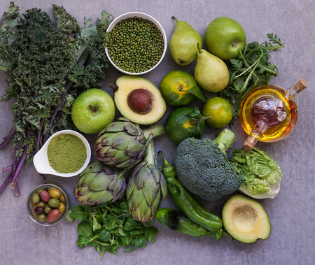 Healthy Green food selection for vegetarians: avocado, apples, broccoli, artichokes, tangerines, mung beans, lettuce, olives, rucola, kale, matcha tea, pears, on gray stone backgroundの写真素材
