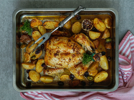 Baked turkey or juicy chicken with golden crispy skin with grapes and potatoes, tangerine. Roasted chicken in baking dish. Christmas dinner. Flat lay. Top viewの写真素材