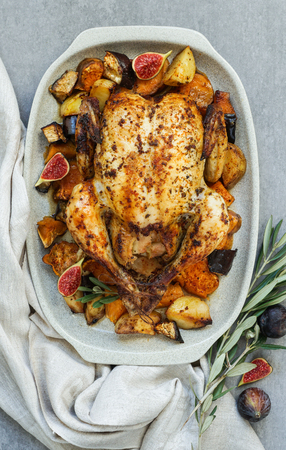 Baked turkey or juicy chicken with golden crispy skin with grapes and potatoes, tangerine. Roasted chicken in baking dish. Christmas dinner. Flat lay. Top viewの写真素材