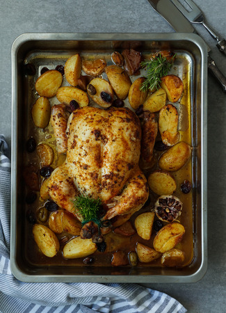 Baked turkey or juicy chicken with golden crispy skin with grapes and potatoes, tangerine. Roasted chicken in baking dish. Christmas dinner. Flat lay. Top viewの写真素材