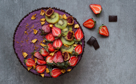 Vegan raw cake with strawberry and kiwi, cashew cream, coconut butter and coconut milk, and base made of almonds, dates and dried apricots, oat flakes, lyophilisated berry, top viewの写真素材