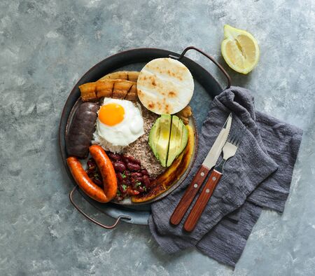 Colombian food. Bandeja paisa, typical dish at the Antioquia region of Colombia - chicharrÃ³n (fried pork belly), black pudding, sausage, arepa, beans, fried plantain, avocado egg, and rice.の写真素材