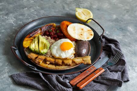 Colombian food. Bandeja paisa, typical dish at the Antioquia region of Colombia - chicharrÃ³n (fried pork belly), black pudding, sausage, arepa, beans, fried plantain, avocado egg, and rice.の写真素材