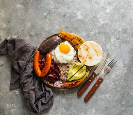 Colombian food. Bandeja paisa, typical dish at the Antioquia region of Colombia - chicharrÃ³n (fried pork belly), black pudding, sausage, arepa, beans, fried plantain, avocado egg, and rice.の写真素材