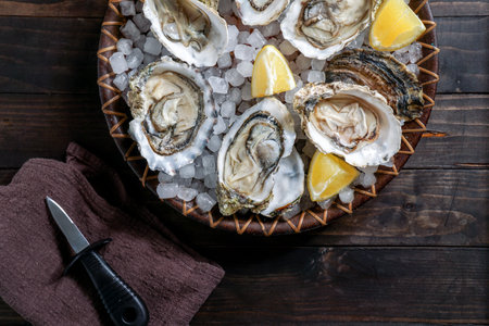 Fresh oysters with ice and lemon on wooden background. Top view