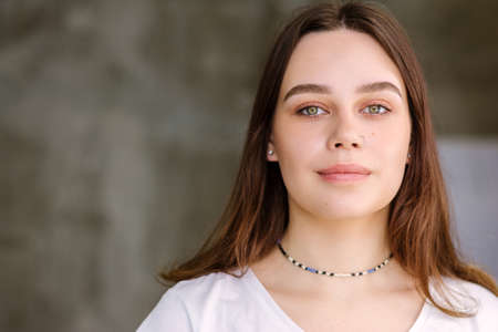Young brunette girl with long hair 16-22 years old with green eyes looks at the camera close-up in a...