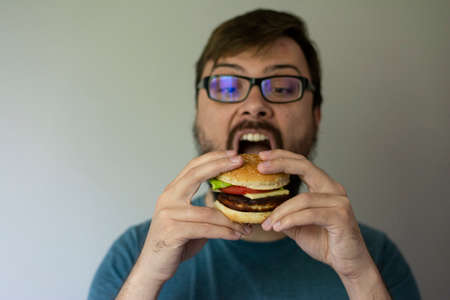 Handsome young brunette man eating hamburger. High quality photoの写真素材
