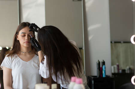 Young woman undergoing eyebrow correction procedure in beauty salon, closeupの写真素材