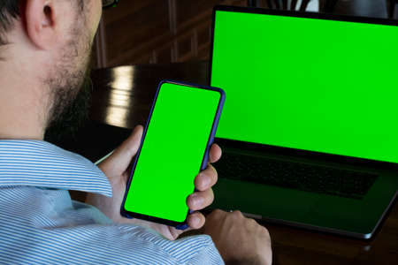 Man with green screen in front of green laptop screen