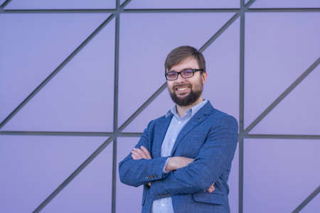 Portrait of successful businessman standing blue wall backgroundの写真素材