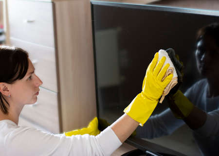 Cleaning service professional house cleaning wiping dust with a rag and in gloves TV displayの写真素材