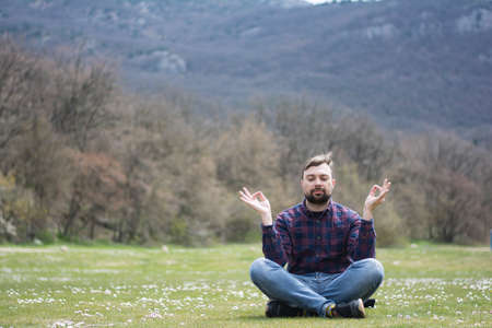 Portrait of handsome man meditating in lotus position outdoorsの写真素材